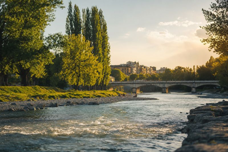 Flussufer in der Stadt an einem Sommerabend mit Steinbrücke